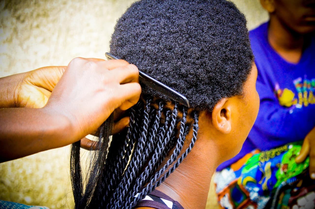 Hands braiding a client's hair into long, neat braids