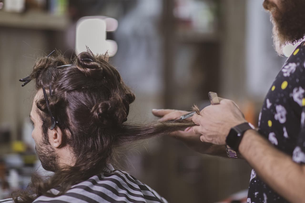 A barber combing out a client's longer hair before cutting it