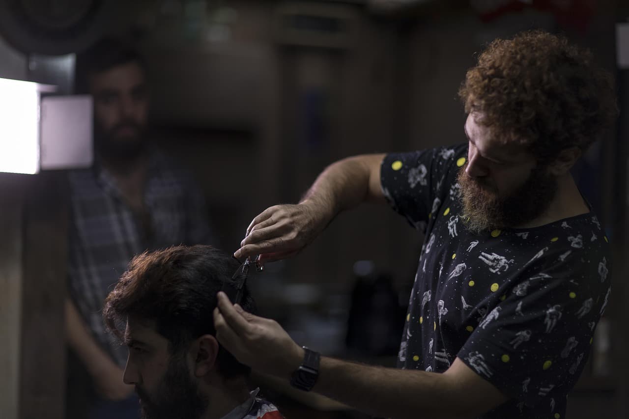 A barber cutting a client's hair under a low lamp
